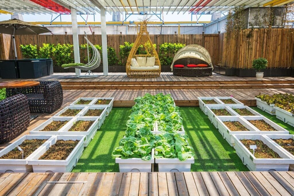 Jardim com horta urbana e áreas de lazer, mostrando canteiros elevados com vegetais em crescimento e móveis de vime para sentar.