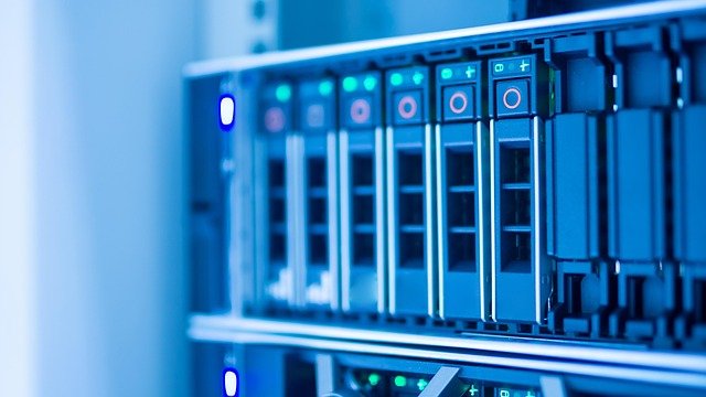 Um plano próximo de uma fila de servidores e hard disks num rack, com luzes indicadoras azuis e verdes a piscar. A imagem representa o hardware essencial de um Data Center. Estes ativos de infraestrutura tecnológica são cada vez mais procurados por alguns FIIs Exóticos para geração de renda.